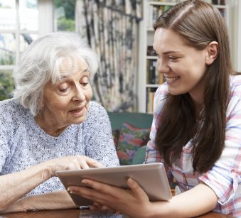 Teenage Granddaughter Showing Grandmother How To Use Digital Tab